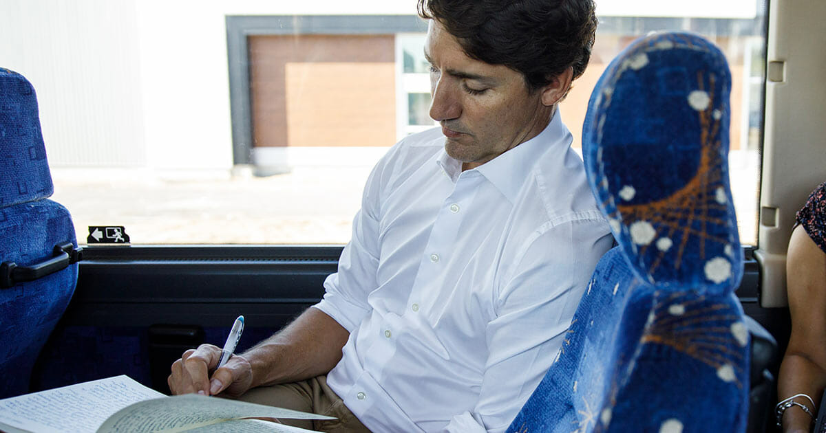 Justin Trudeau taking notes inside of a bus.