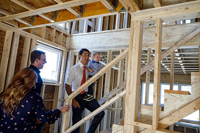 Justin Trudeau visits a new housing development in Sackville. He is holding a toddler while going up the stairs.